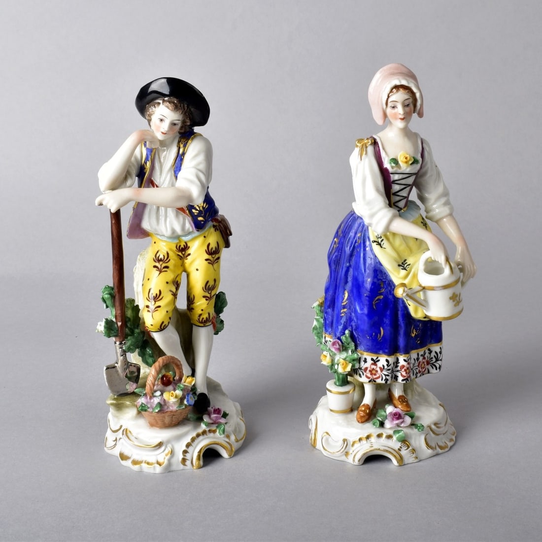 Pair Antique Chelsa Figurines: Pair Antique Chelsa Figurines. A man holding a shovel and a woman with a watering can. 7-3/4"H x 3"Dia. Condition: Amazingly the flowers to the front of the woman are still intact but the back the tre
