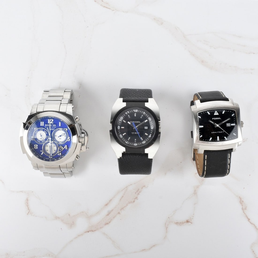 Three Men's Vintage Stainless Steel Watches: Lot of Three Men's Vintage Stainless Steel Watches. Lot includes a Fossil Arkitekt with black dial and leather bracelet, Invicta Reserve Chronograph with blue dial and stainless steel bracelet, and a