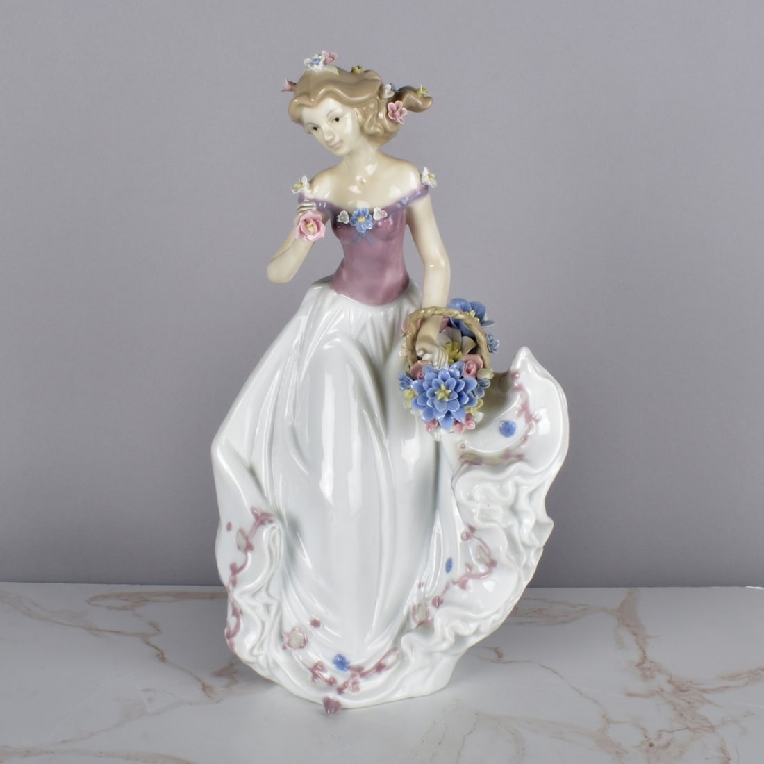 Lladro Syle Porcelian Lady Figurine: Lladro Syle Porcelian Lady Figurine. Girl with Basket of flowers in the wind. Unsigned. Measures 14-1/2" H x 8-1/2" W x 6". Condition: Good condition, i see no loss of flowers but. No Box. Estimate: $