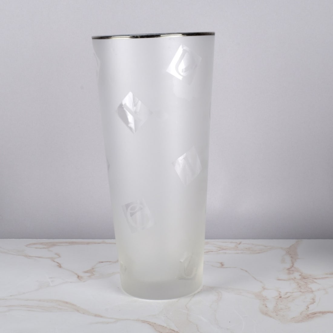 Gucci Frosted Art Glass Vase: Gucci Frosted Monogram Art Glass Vase, silver rim with etched letters scattered to spell Gucci . Measures 11-3/4" H x 5-1/2" D. Condition: Good used condition, pontal not smooth. Estimate: $50.00 - $1