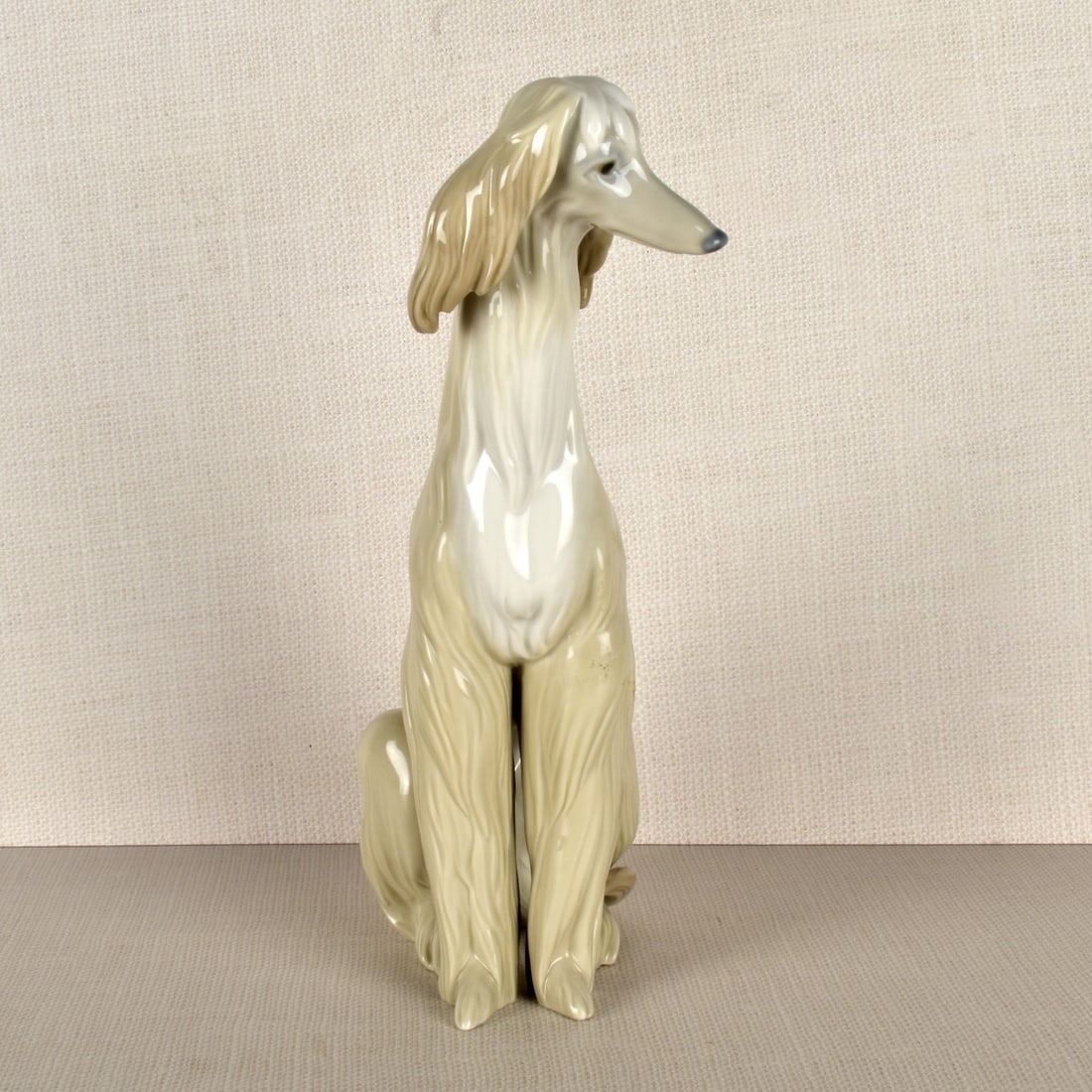 Lladro Figurine of an Afghan: Lladro Porcelain Figurine of an Afghan Sitting on its Hind Legs. Properly marked on the bottom. Measures: 12" H, 4" W, 6-1/2" D. Condition: Good condition. Estimate: $100.00 - $200.00 Domestic Shippin