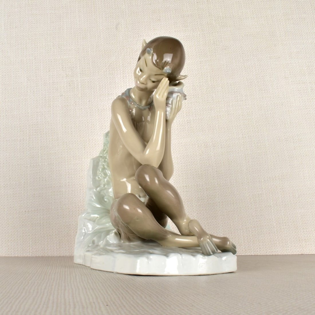 Lladro Figurine of a Satyr: Lladro Figurine of a Young Satyr With a Conch Shell To His Ear. Properly marked on the bottom. Measures: 8-3/4" H, 4-1/2" W, 8" D. Condition: Good condition. Estimate: $50.00 - $100.00 Domestic Shippi