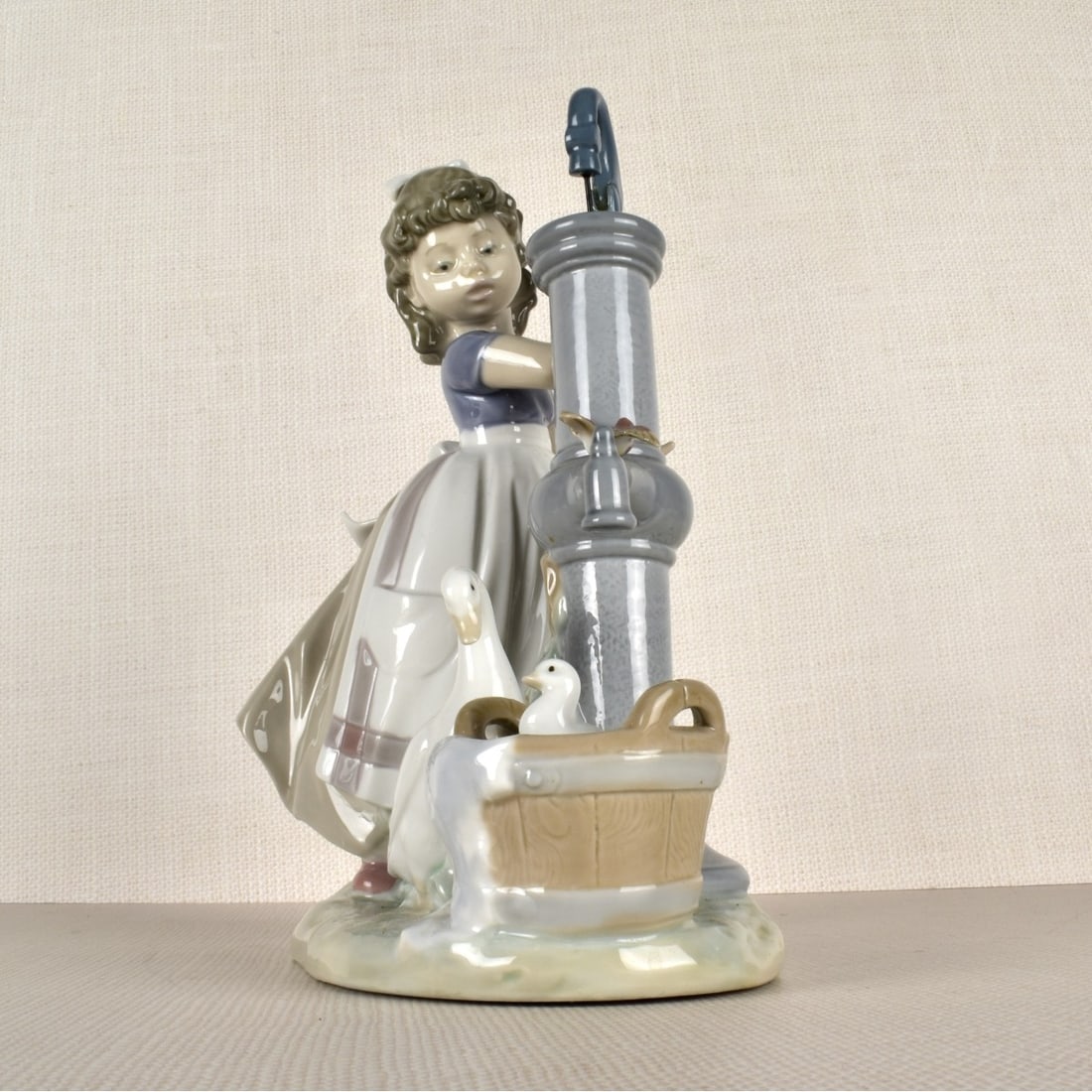 Lladro Porcelain Figurine: Lladro Porcelain Figurine Titled " Summer On The Farm" A young girl at the water pump with two (2) geese, one looking on while one is in a bucket of soapy water bathing. Issued: 1985, Retired 2007.Pro