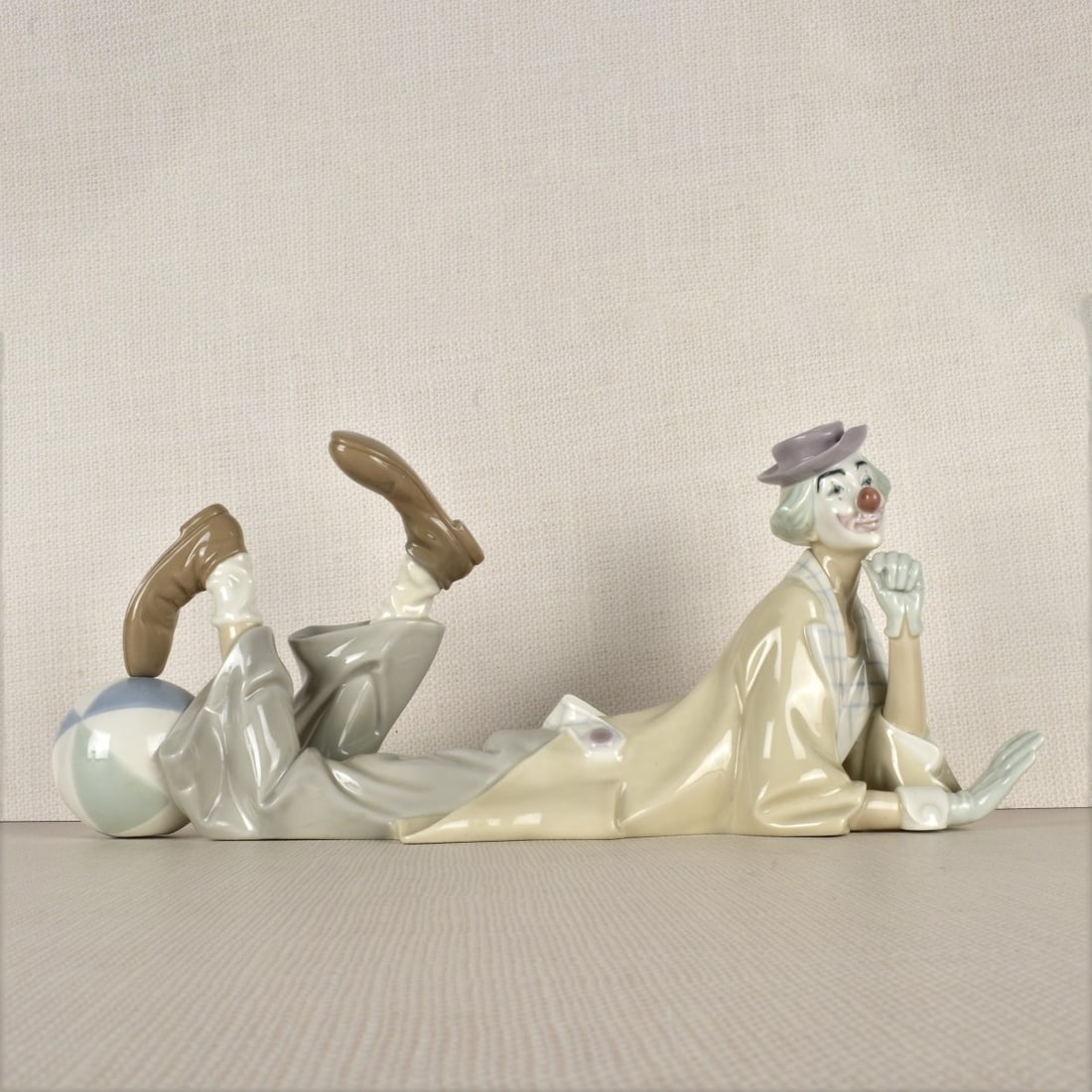 Lladro Figurine of a Clown with a Ball: Lladro Figurine of a Clown Laying Down with His Foot Resting on a Ball. Properly marked on the bottom. Measures: 6-3/4" H, 14-1/2" W, 4-3/4" D. Condition: Good condition. Estimate: $100.00 - $200.00 D