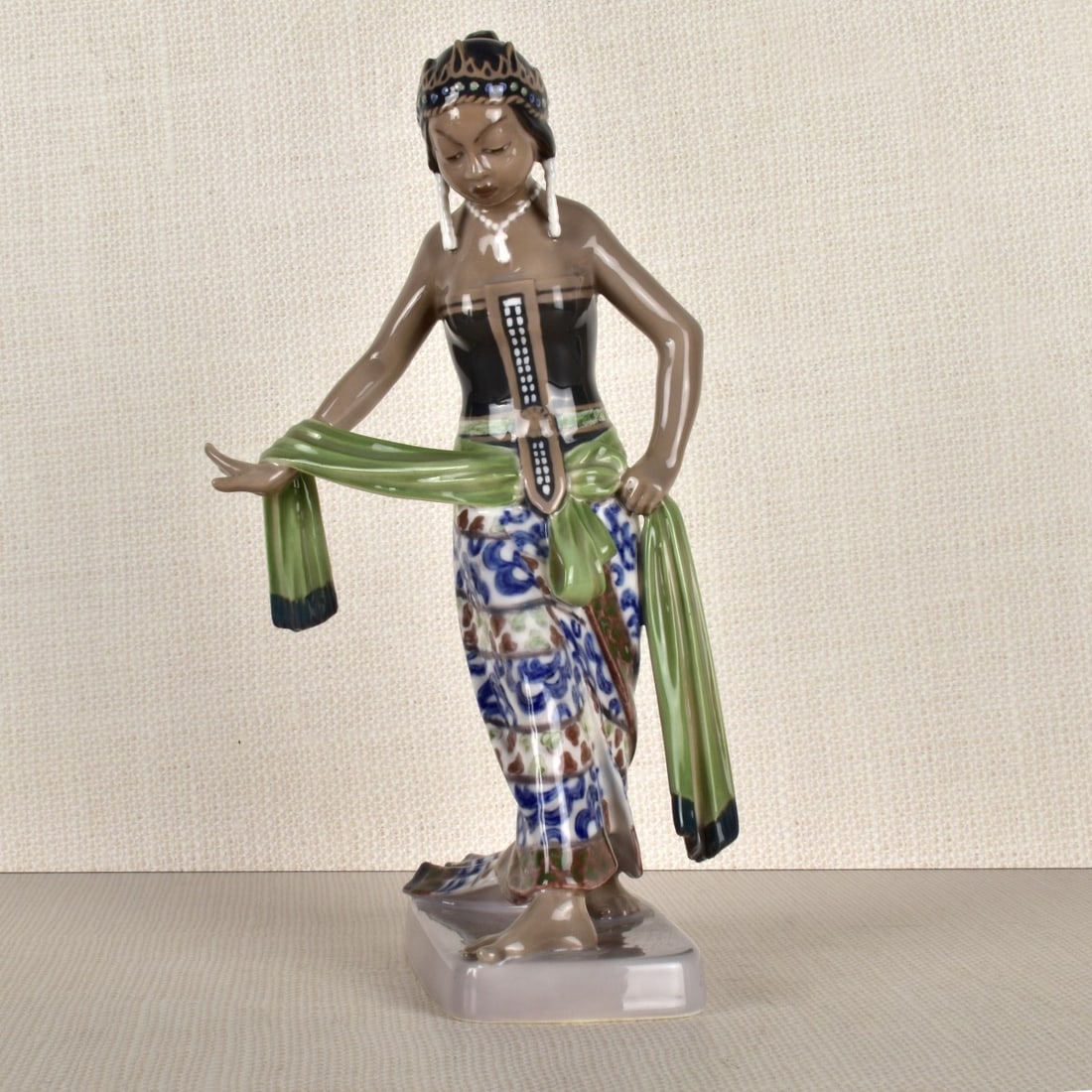 Porcelain Figurine of a Dancer: Porcelain Figurine of a Polynesian Dancer Holding a Scarf, Stamped "D.J. Copenhagen, 1114" on the Bottom. Measures: 9-1/4" H, 5-1/2" W, 4-3/4" D. Condition: Good condition. Estimate: $50.00 - $150.00 