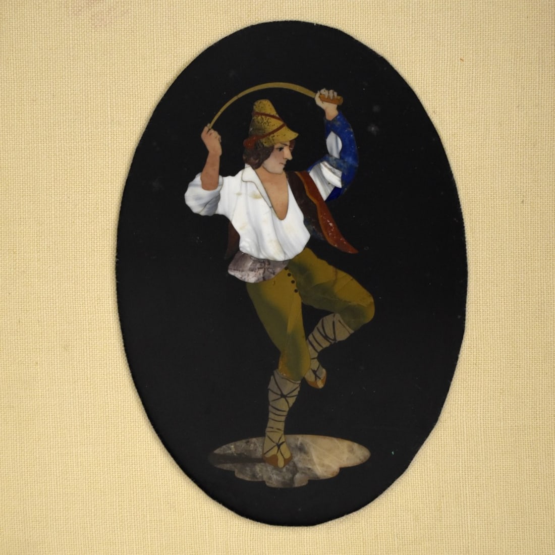 Italian Pietra Dura Plaque: Italian Pietra Dura Oval Plaque of a Man Bending a Whip Over His Head While Dancing. Circa late 20th century. Plaque viewing area measures: 6-1/2" H, 4-1/2" W, frame measures: 15" H, 13" W. Condition: