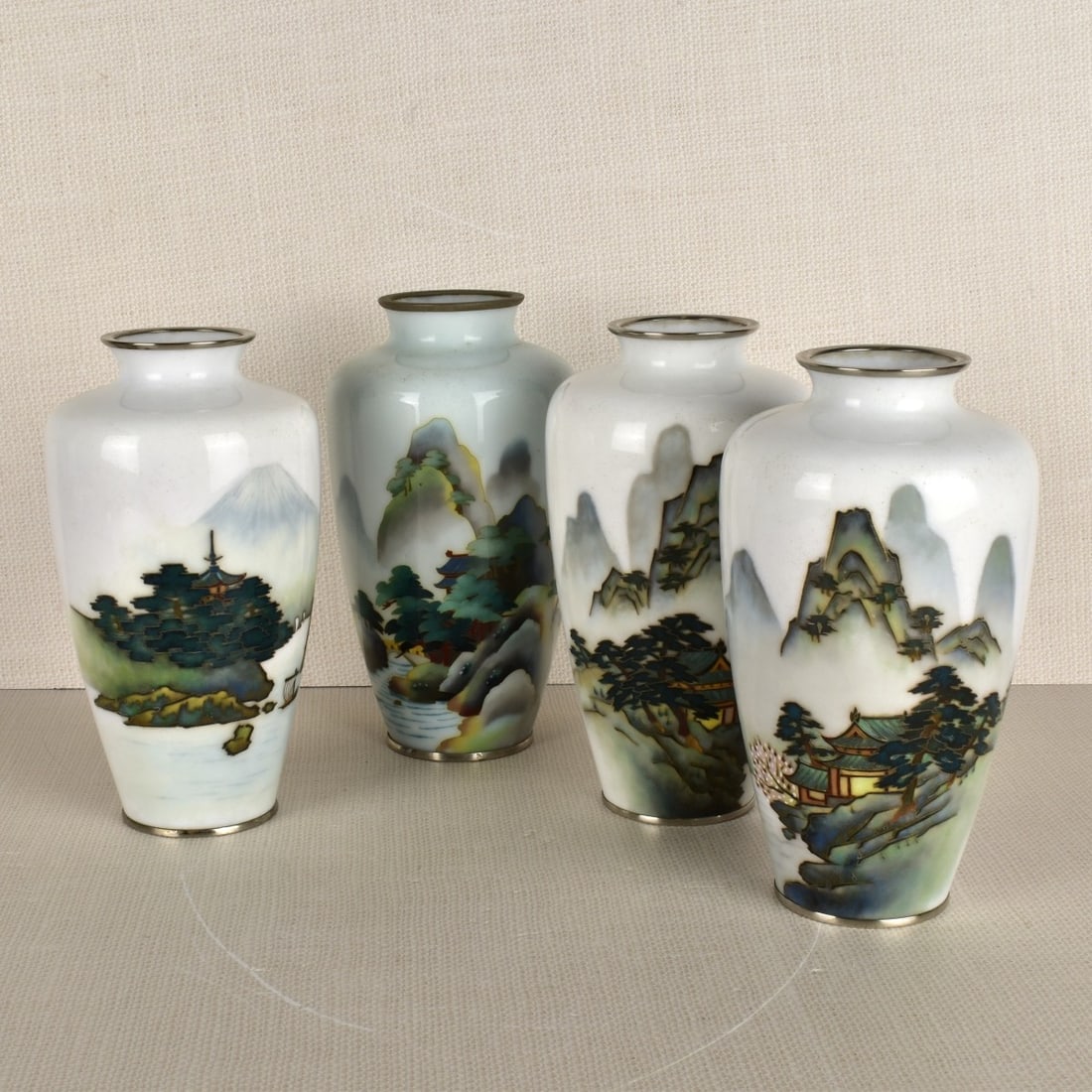 Collection of Four (4) Japanese Cloisonne Vases: Collection of Four (4) Japanese Cloisonne Vases. Enameled with various scenes of mountain ranges and river scenes on white grounds. 20 th century. Measures: 7-1/2" H, 4" Dia. Condition: Good condition