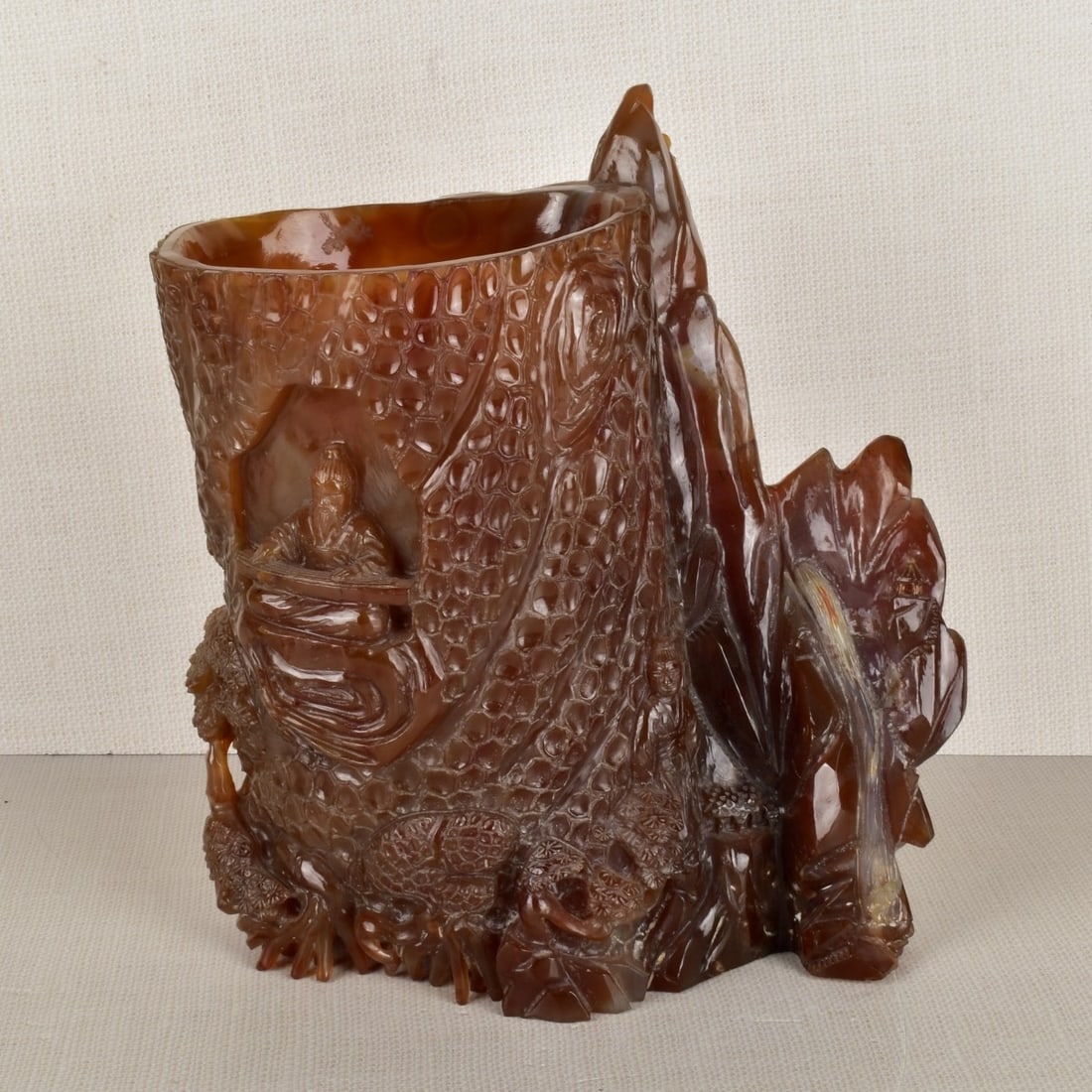 Chinese Natural Carnelian Brush Pot: Chinese Natural Carnelian Brush Pot Carved Deeply with Figures and Brush All Around. Incised artist on the back. Late 19th century. Measures: 11-1/8" H, 11" W, 6-1/2" D. Condition: Good condition. Est