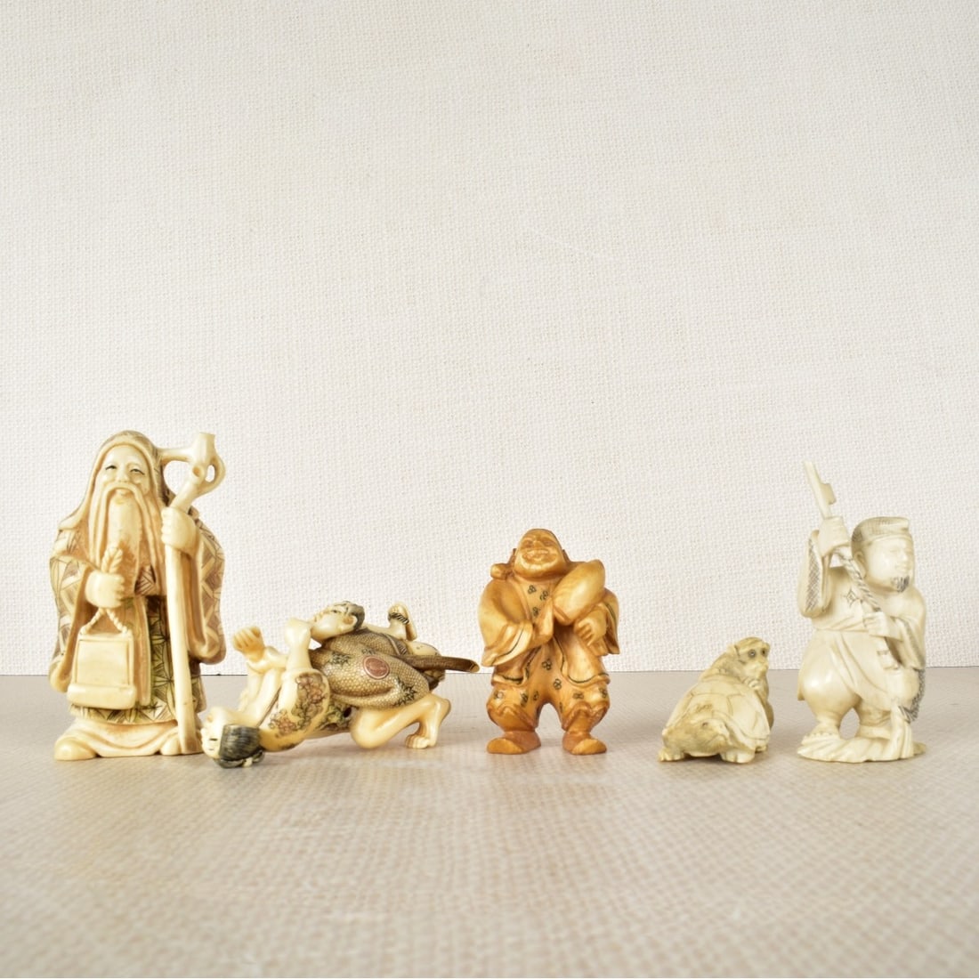 Five Asian Hand Carved Netsuke Figurines: Five Asian Hand Carved Polychrome Netsuke Figurines, an erotic couple, a man with fish, an Okimono, a turtle and monkey, and a tea stained man. Largest measures 3" H x 1-1/2" W. We Will Not Ship This