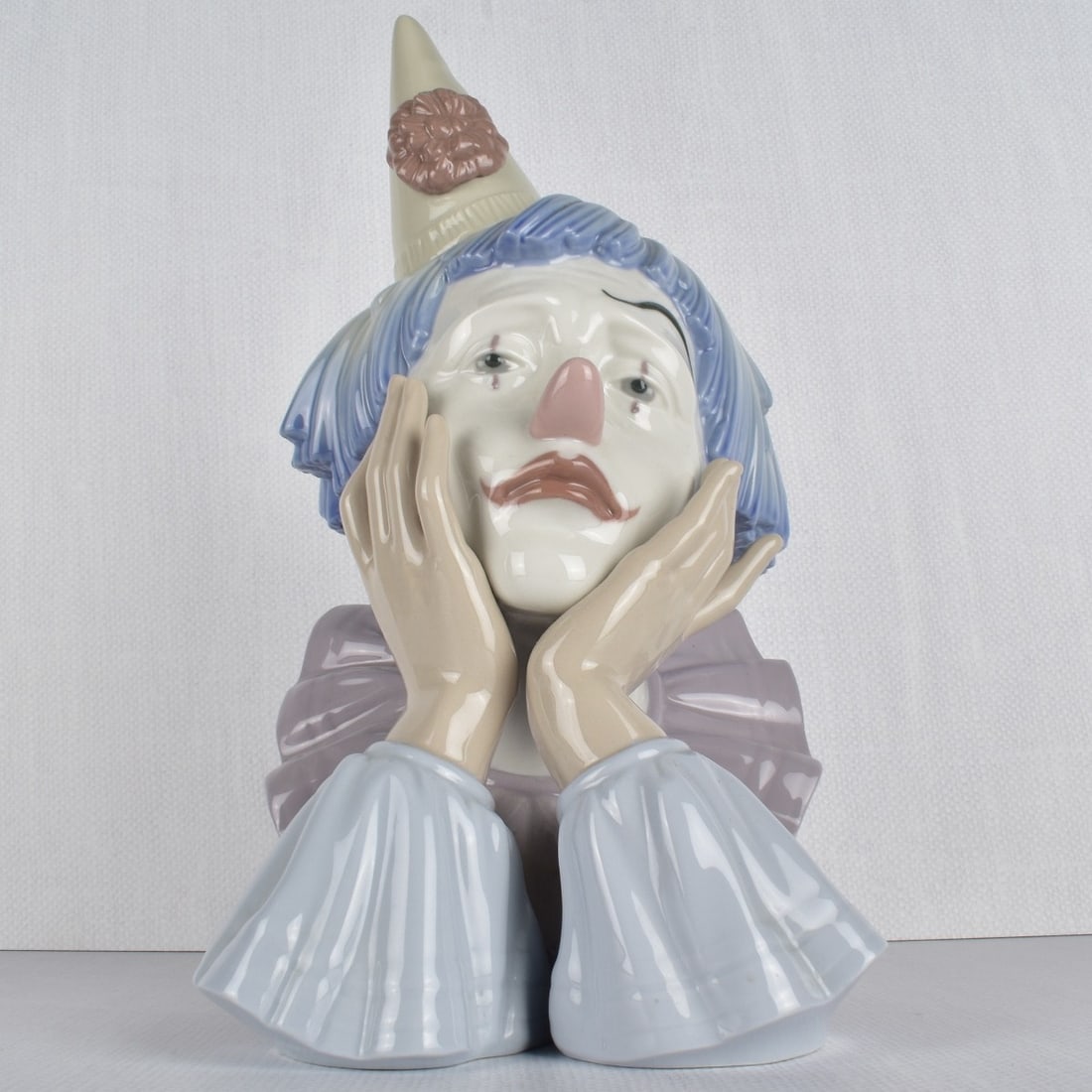 Lladro Porcelain Figurine of a Clown: Lladro Porcelain Figurine of a Sad Clown with his Hands to his Face. Properly marked to the bottom. Measures: 12" H, 6-1/2" W, 8" D. Condition: Good condition. Estimate: $100.00 - $150.00 Domestic Shi