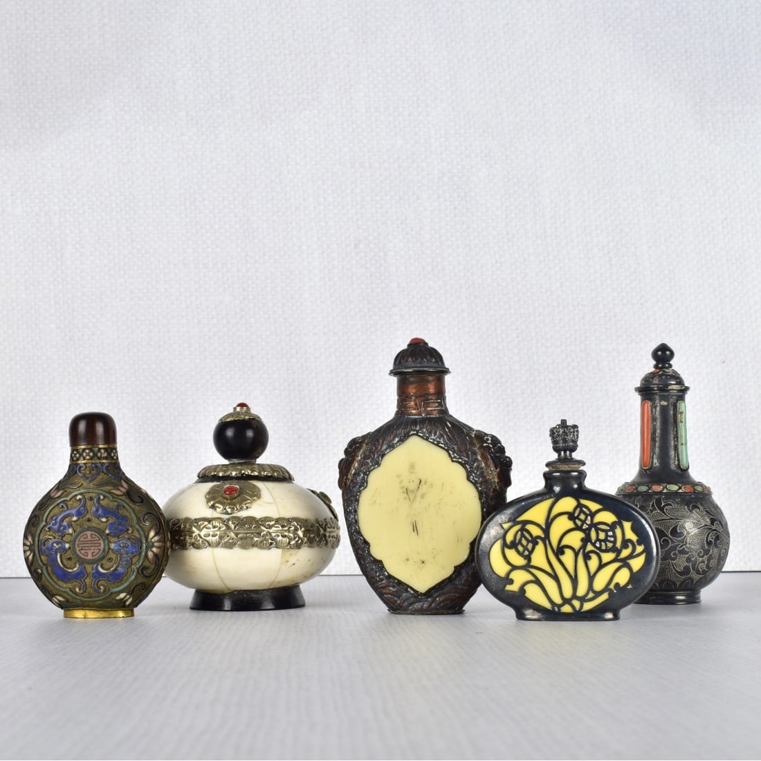 Chinese Snuff Bottles: Five (5) Chinese Assorted Snuff Bottles, different materials, silver clad, bone, celluloid, brass, metal, cloisonné some with inlaid stones. Tallest measures: 3-1/4" H, 2-1/2" W, smallest measures: 2