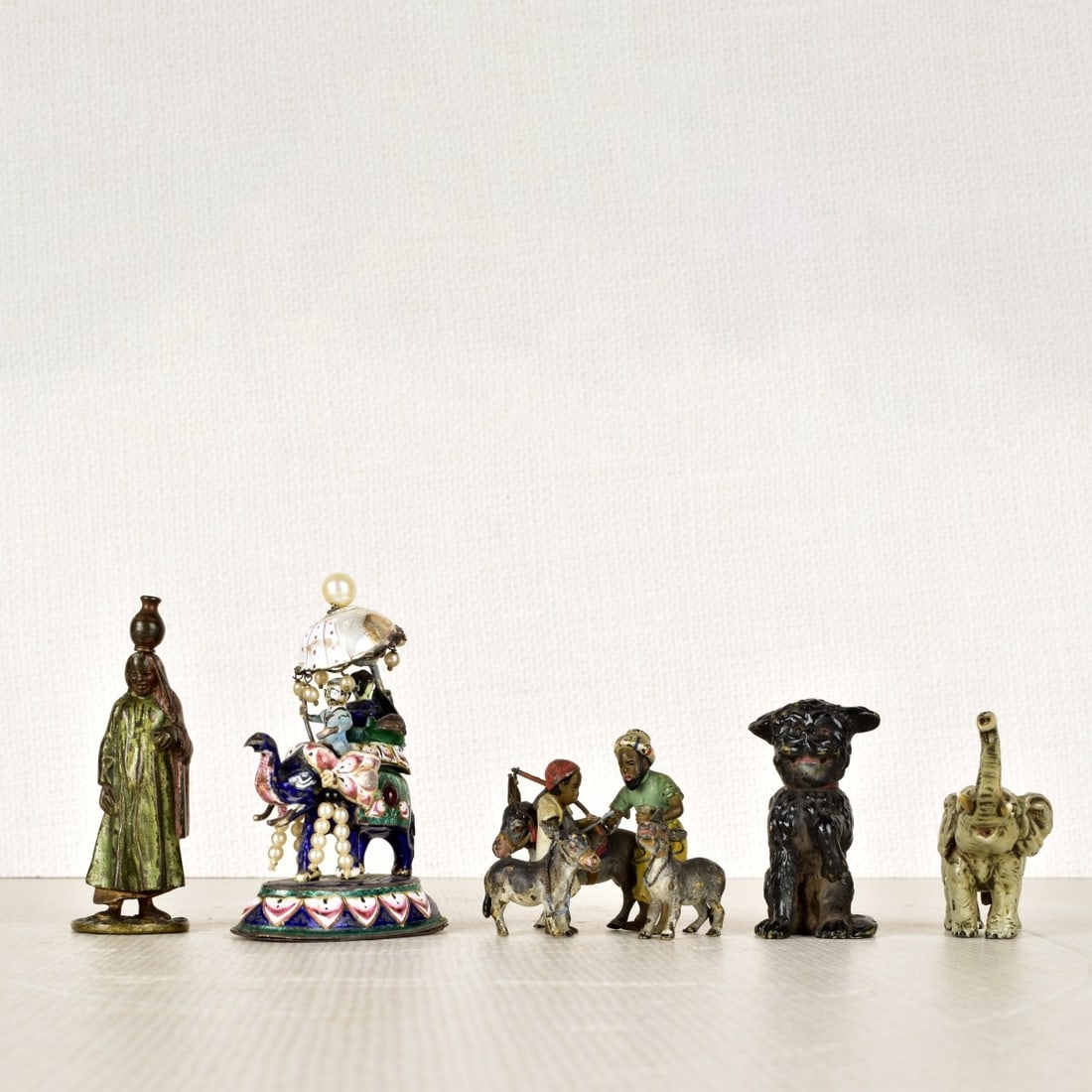 Five (5) Cold Painted Bronze Sculptures: Group of Five (5) Cold Painted Bronze Sculptures. One(1) figure of a Arab woman with a jug resting on her head, one (1) elephant with tusk up, one (1) small dog with his paw up and one (1) figurine of