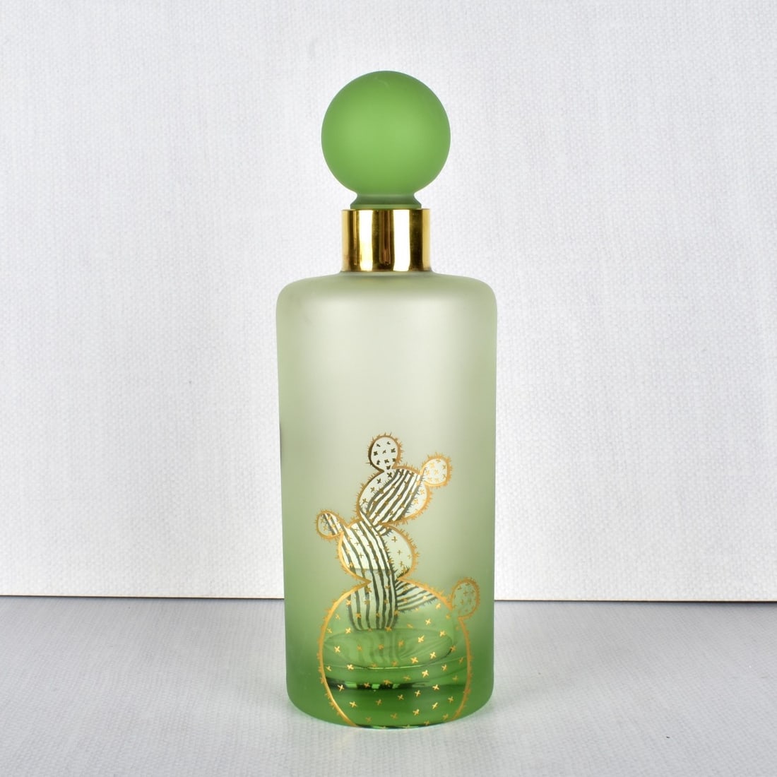 Daum Glass Decanter: Daum Green Glass Decanter Decorated with Gold Enameled Cactus with a Large Ball Glass Stopper. Signed "Daum France" on the bottom. Measures 10-1/8" H, 3-1/2" Dia. Condition: Good condition. Estimate: