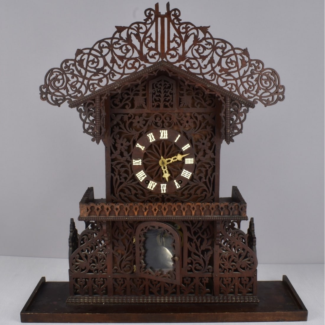 German Dark Wood Scroll Clock: Antique German Hand Carved Dark Wood Scroll Carved Clock if the Form of A German Chalet, with key. Measures: 23-1/4" H, 21-3/4" W, 7-1/2" D. Condition: Good antique condition. Please note the gallery 