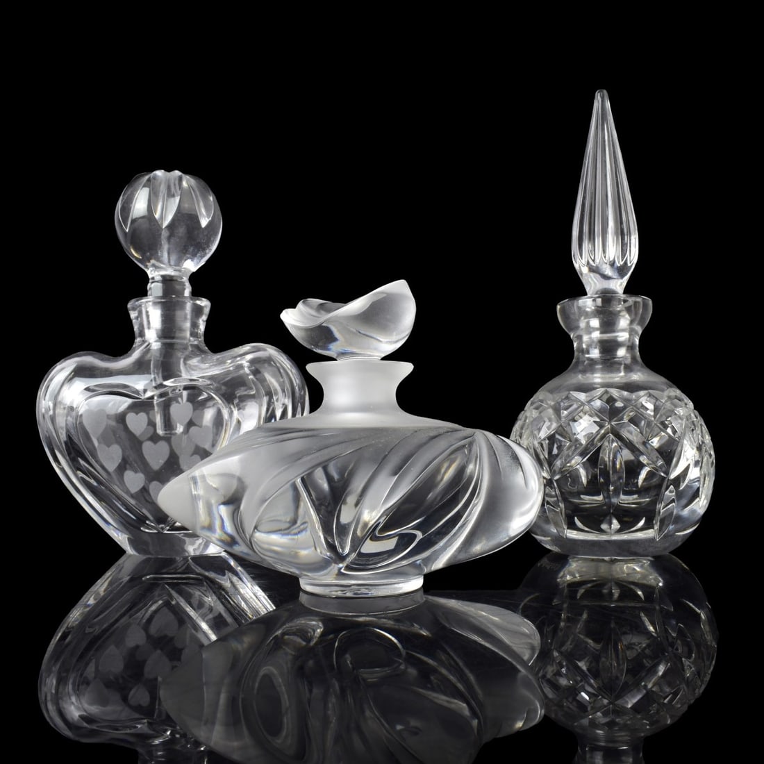 Lalique and Waterford Perfume Bottles: Three (3) Perfume Bottles. Consisting of two (2) Waterford bottles and one (1) Lalique Bottle. All properly marked to the bottom. Tallest measures: 6-1/4" H, 2-1/2" Dia. Condition: Good condition. Est