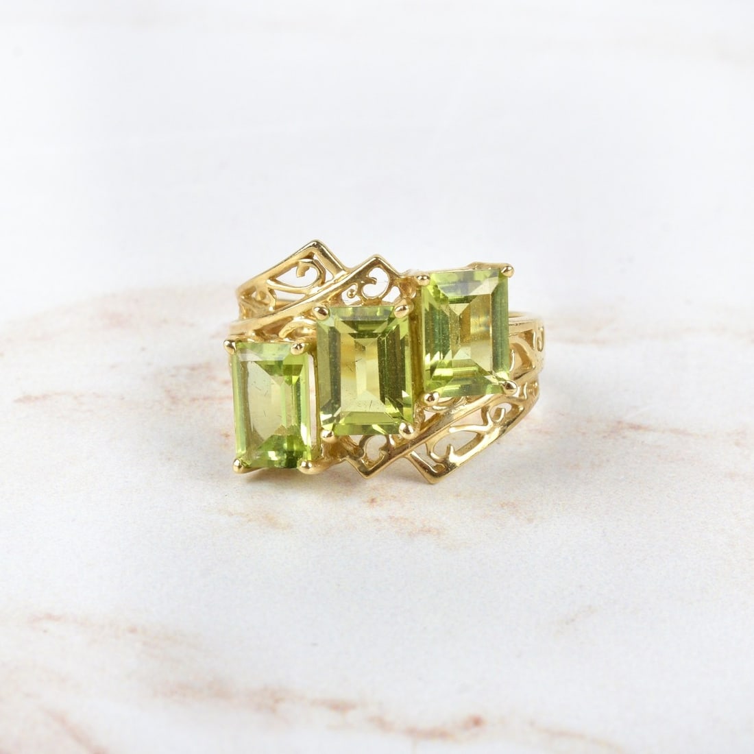 Peridot and 10K Ring: Emerald Cut Peridot and 10 Karat Yellow Gold Three Stone Ring. Stamped 10K. Ring size 5. Approx. weight: 3.30 grams. Condition: Very good condition. Estimate: $150.00 - $250.00 Domestic Shipping: $40.