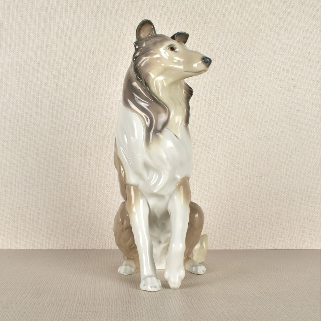 Lladro Figurine of a Collie: Lladro Porcelain Figurine of a Collie on His Two Hind Legs with One Paw Bent Up. Properly marked on the bottom. Measures:10" H, 8-3/4" W, 5" D." Condition: Good condition. Estimate: $100.00 - $200.00 