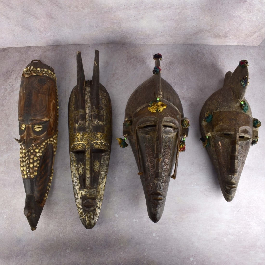 African Polychrome Carved Wood Masks: Four (4) African Polychrome Carved Wood Masks. All appearing to be west African in origin. 20th century. Longest measures: 22" L. Kodner Galleries offers phone and absentee bidding at a low, flat 21% 