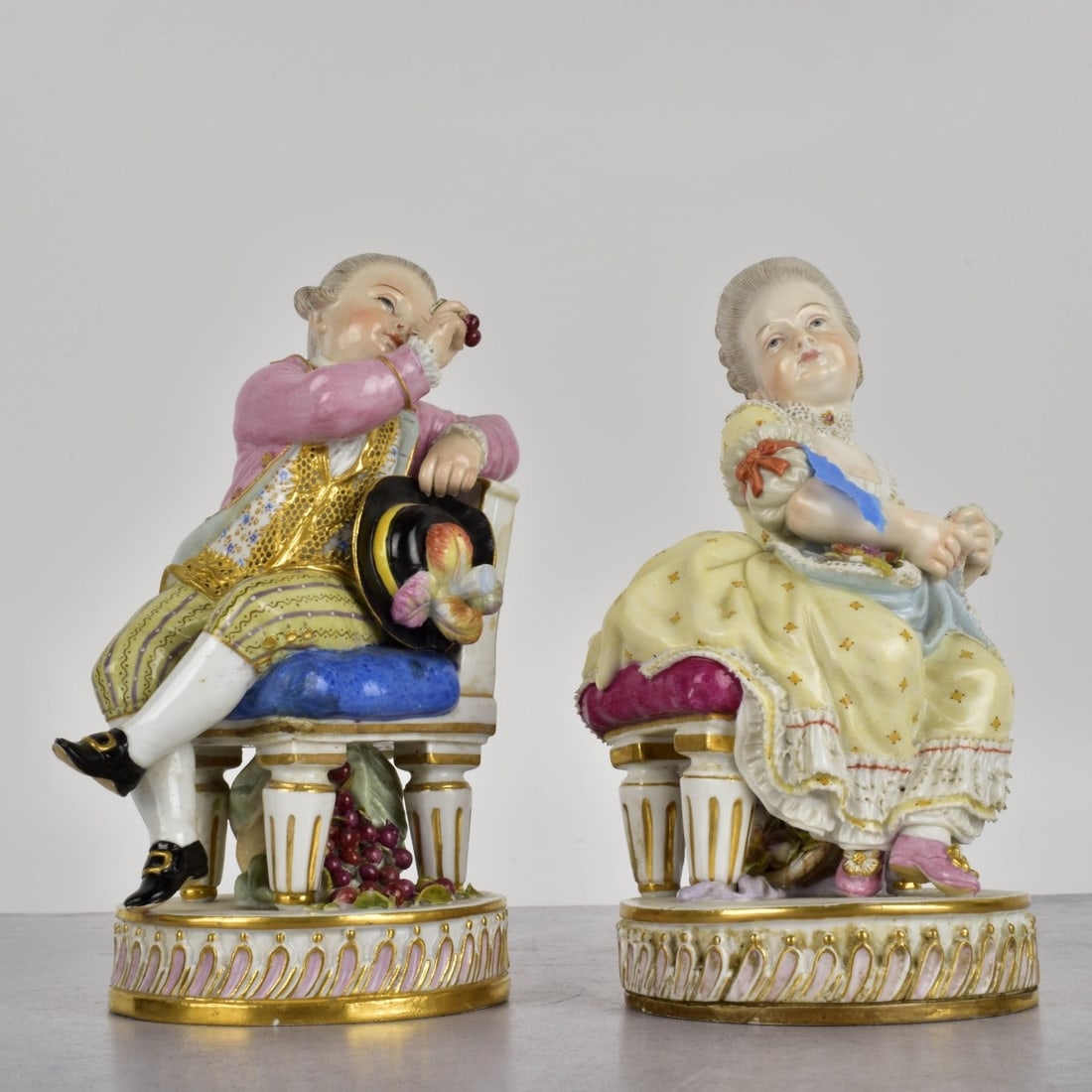 Meissen Porcelain Figurines: Meissen Porcelain Figurines. A young man offering cherries to a young woman holding a book. Measures: 5-1/2" H., 3" W. Kodner Galleries offers phone and absentee bidding at a low, flat 21% buyer’s p