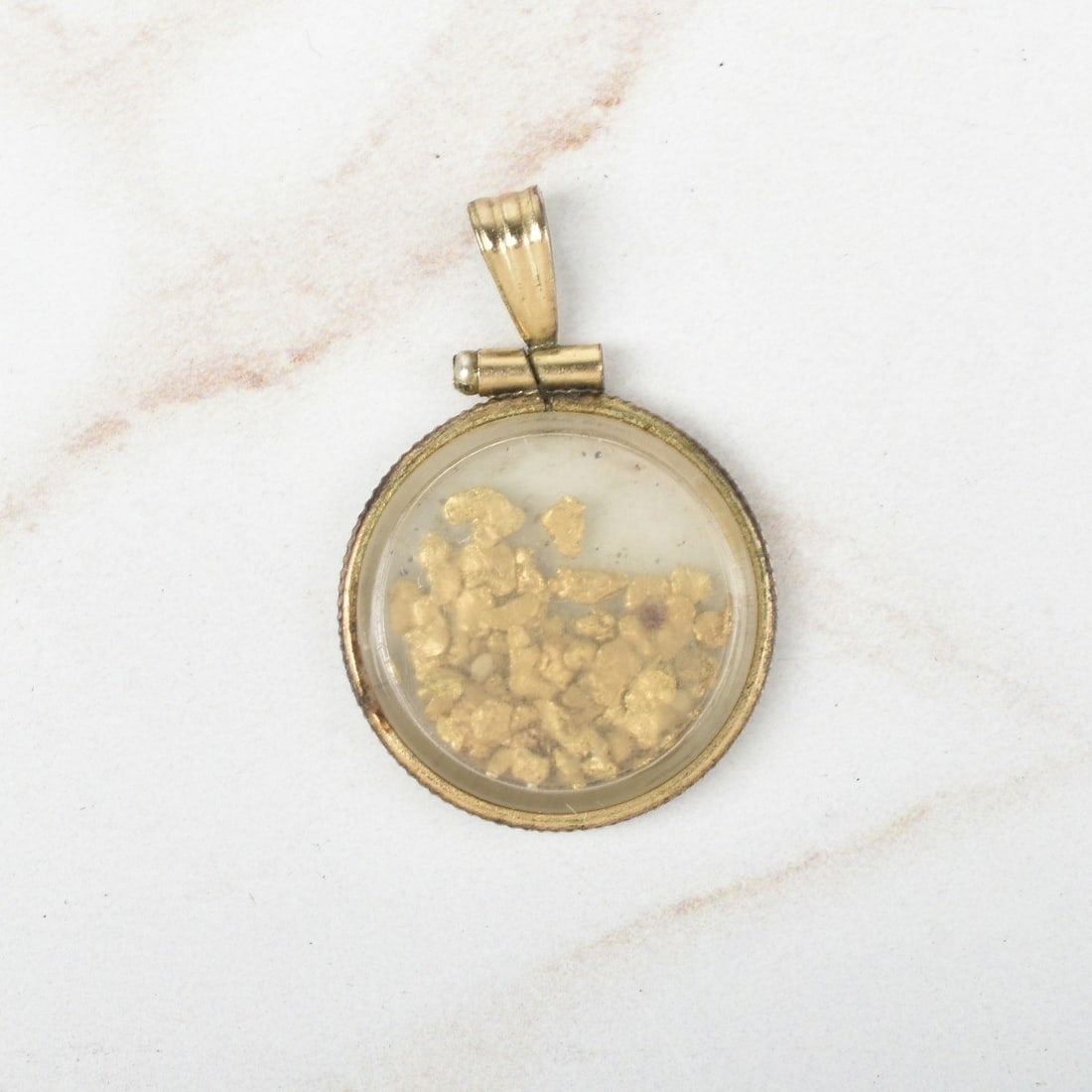 Gold Nugget Pendant: Vintage Gold Nuggets Encased in Gold Tone Metal Shadow Box Pendant. Measures 1" L, 3/4" W. Kodner Galleries offers phone and absentee bidding at a low, flat 21% buyer’s premium without surcharge or 