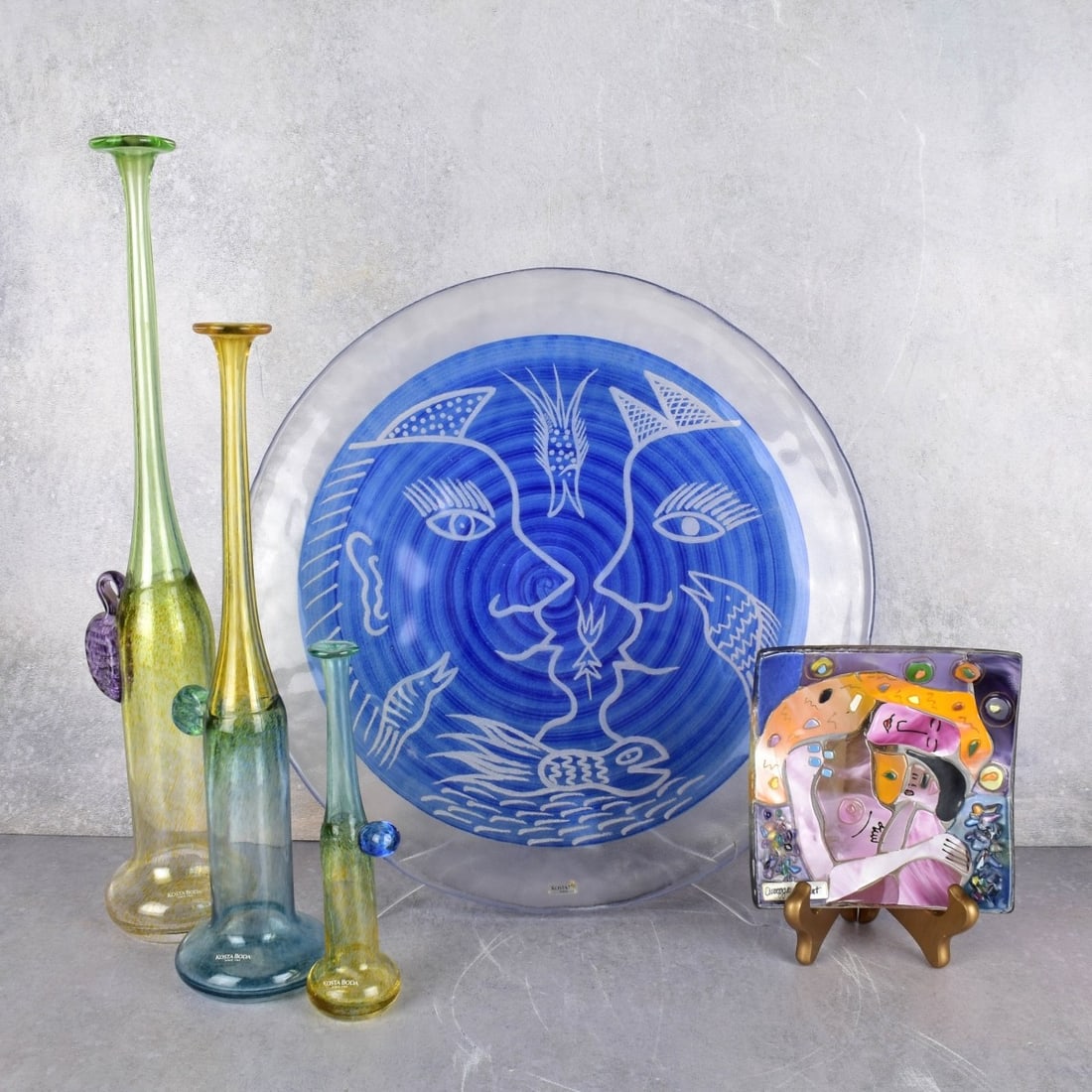 Vintage Kosta Boda Glass Pieces: Five (5) Vintage Kosta Boda Glass Pieces. Consisting of one (1) Kosta Boda charger by Ulrica Hyndman-Vallien, blue paint with a clear-frosted boarder with the center painted of profiles and fish, meas