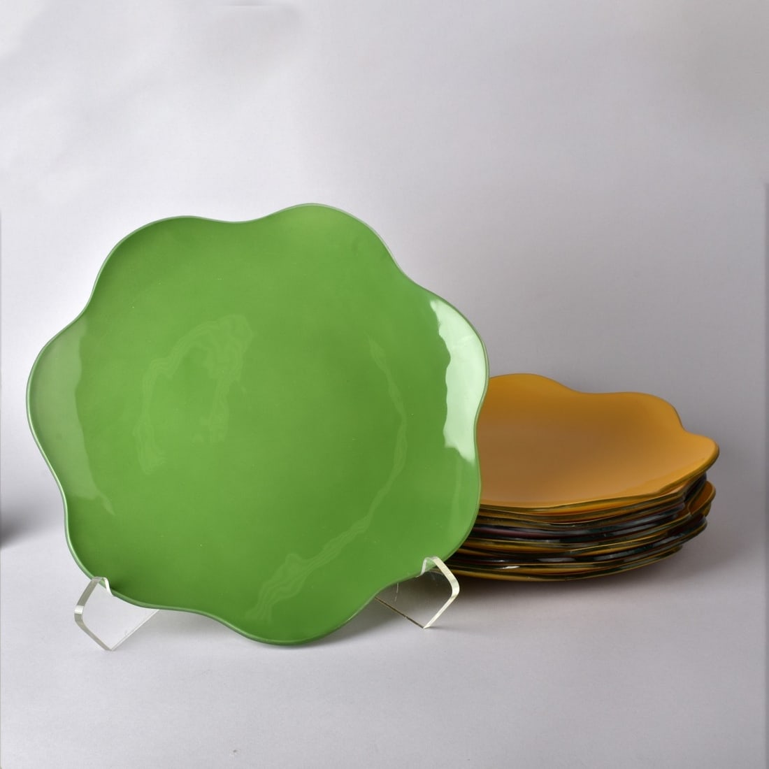 Annieglass Handmade Glass Chargers: Eleven (11) Vintage Annieglass Handmade Glass Chargers with Scalloped Edges. Artist signed and numbered. Measures: 1" H, 13-1/4" Dia. Kodner Galleries offers phone and absentee bidding at a low, flat 