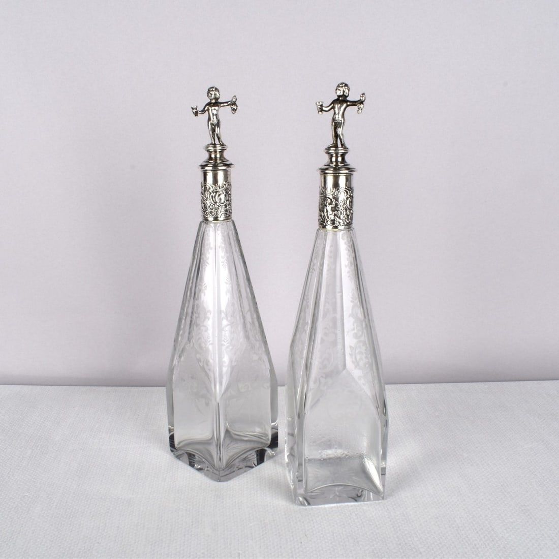 Continental Silver and Etched Bottles: Pair of Continental .800 Silver Etched Bottles with Stoppers. Square bottoms conforming with angular sides and stoppers finished with young children holding grape clusters and wine glasses. Unsigned. 