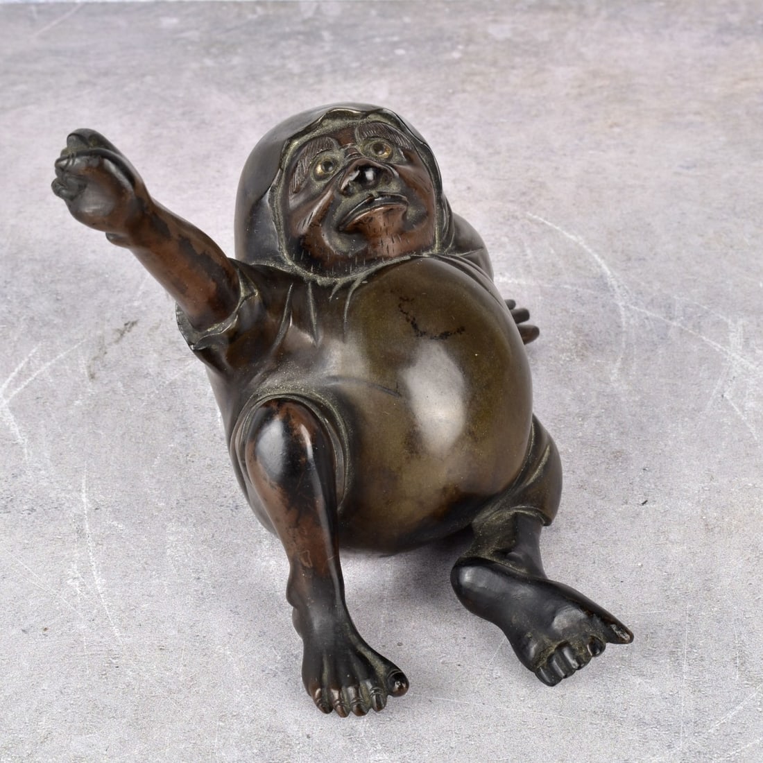 Meiji Period Figurative Japanese Bronze: Meiji Period, 1868-1912 Heavy Japanese Figure of a Seated Man Grasping Something in his Raised Hand. Measures: 5" H., 6-1/2" W., 5" D. Kodner Galleries offers phone and absentee bidding at a low, flat