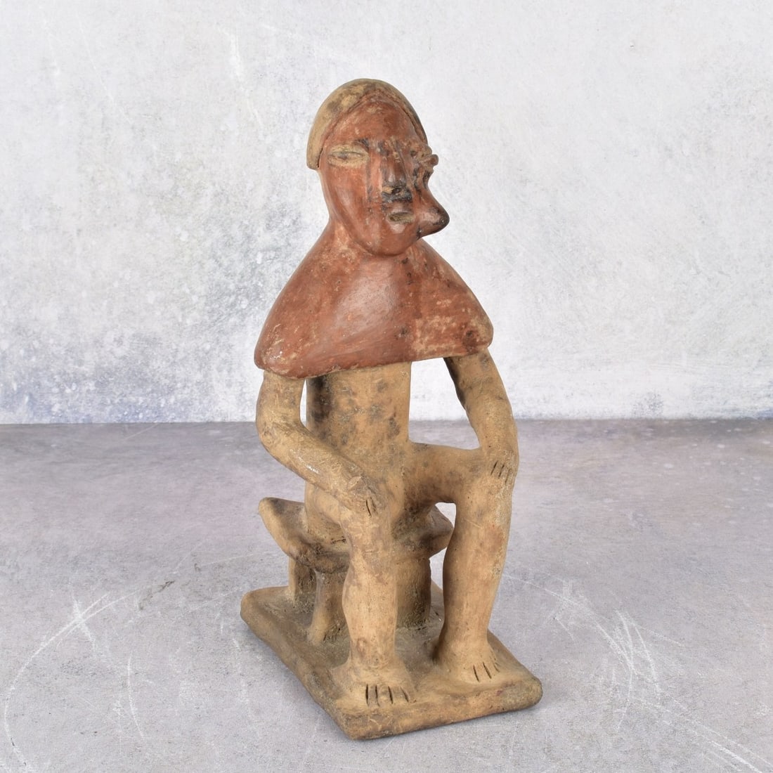 Antique South American Terracotta Figurine: Antique South American Terracotta Figurine of Seated Person Appearing to Have a Mouth Full of Peyote. Measures: 8" H., 2-7/8" W., 4 1-8" D. Kodner Galleries offers phone and absentee bidding at a low,