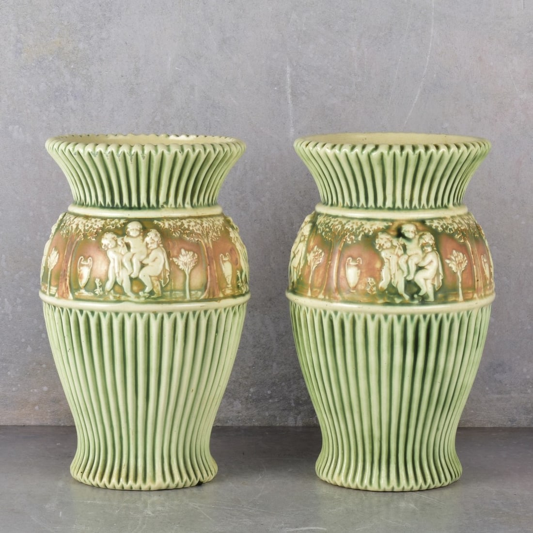 Roseville "Donatello" Pottery Vases: Roseville "Donatello" Pottery Vases. Decorated in high relief with children at play swinging in swings under large trees.CIrca 1930. Measures: 12" H, 7" Dia. Kodner Galleries offers phone and absentee