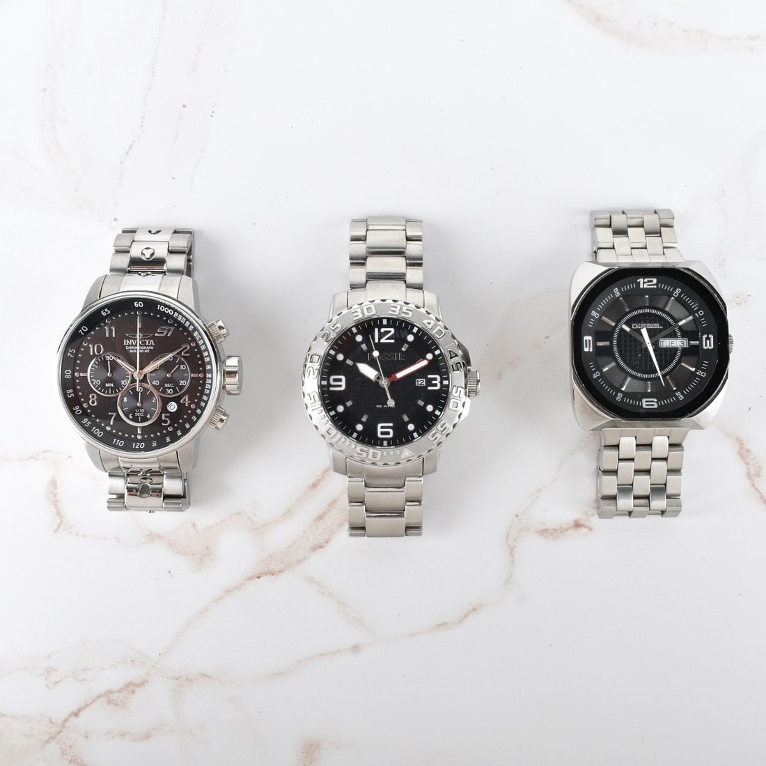 Three Men's Stainless Steel Watches: Lot of Three Men's Stainless Steel Watches. Lot includes a Fossil 10 ATM with black dial, Invicta Chronograph with black dial, and a Diesel with black dial. Invicta measures 48mm. Fossil measures 48mm