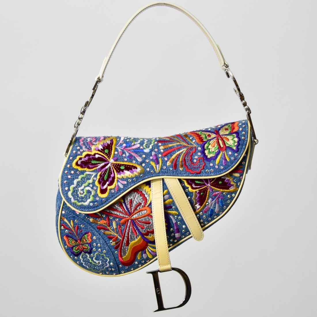 Christian Dior Embroidered Saddle Bag: John Galliano for Christian Dior Embroidered Saddle Bag with Jewels. Silver tone hardware and cream patent leather trim. Label to interior. Measures 7" H, 9-1/4" W, 6-1/2" L handle drop. With box and