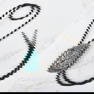 Navajo Turquoise and Sterling Bolo Tie: Vintage Navajo Turquoise and Sterling Silver Bolo Tie with Braided Leather. Signed "N.E'" stamped sterling. Slider measures 2-1/2" H, 2" W; tie measures 43" L. Approx. gross weight: 80.91 grams.