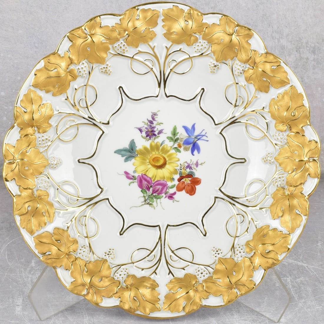 Meissen Porcelain Circular Plate: Meissen Porcelain Circular Plate With Heavy Gold Decoration with a Central Medallion of Painted Flowers and Raised Foliage Edge. Marked with the Meissen crossed swords under glaze and incised numbers.