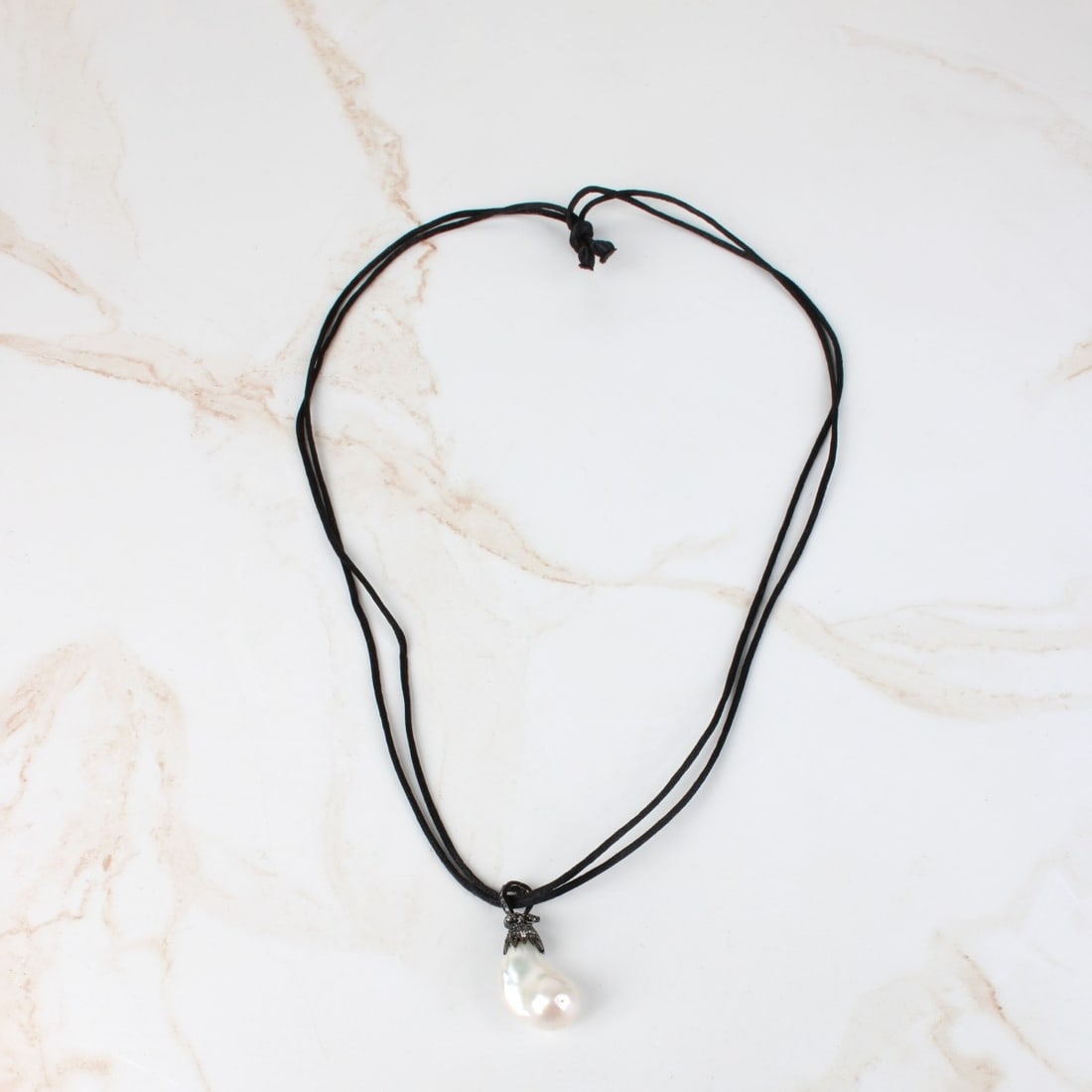 Large Baroque Pearl Necklace: Large Baroque Pearl, Black Metal and Black Silk Pendant Necklace. Pearl with good luster and polish. Measures 25.5 x 17.5mm. Silk measures 31" L. Provenance: former South Florida jewelry designer / ma