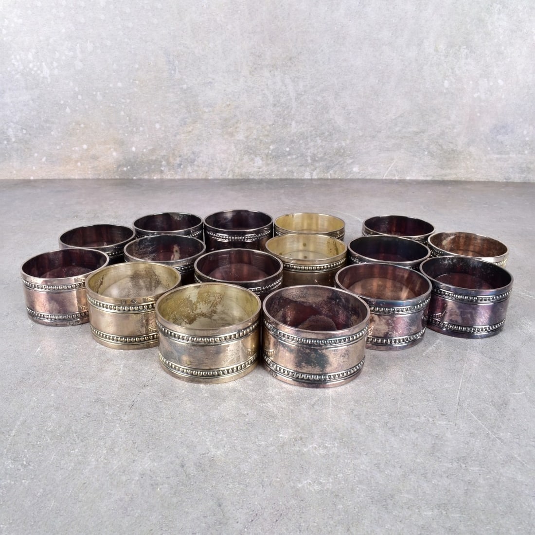 Gump's Silver Plated Napkin Holders: Sixteen (16) Gump's Silver Plated Napkin Holders. Measures: 1" H., 1-3/4" Dia. Kodner Galleries offers phone and absentee bidding at a low, flat 21% buyer’s premium without surcharge or hidden fees.