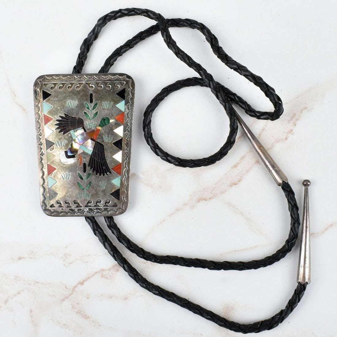 Zuni Hardstone and Silver Bolo Tie: Vintage Zuni Black Onyx, Red Coral, Turquoise and Mother of Pearl Inlaid Silver Bolo Tie with Braided Leather. Slider measures 2-3/4" H, 2" W; tie measures 36" L. Approx. gross weight: 50.65 grams. Ko
