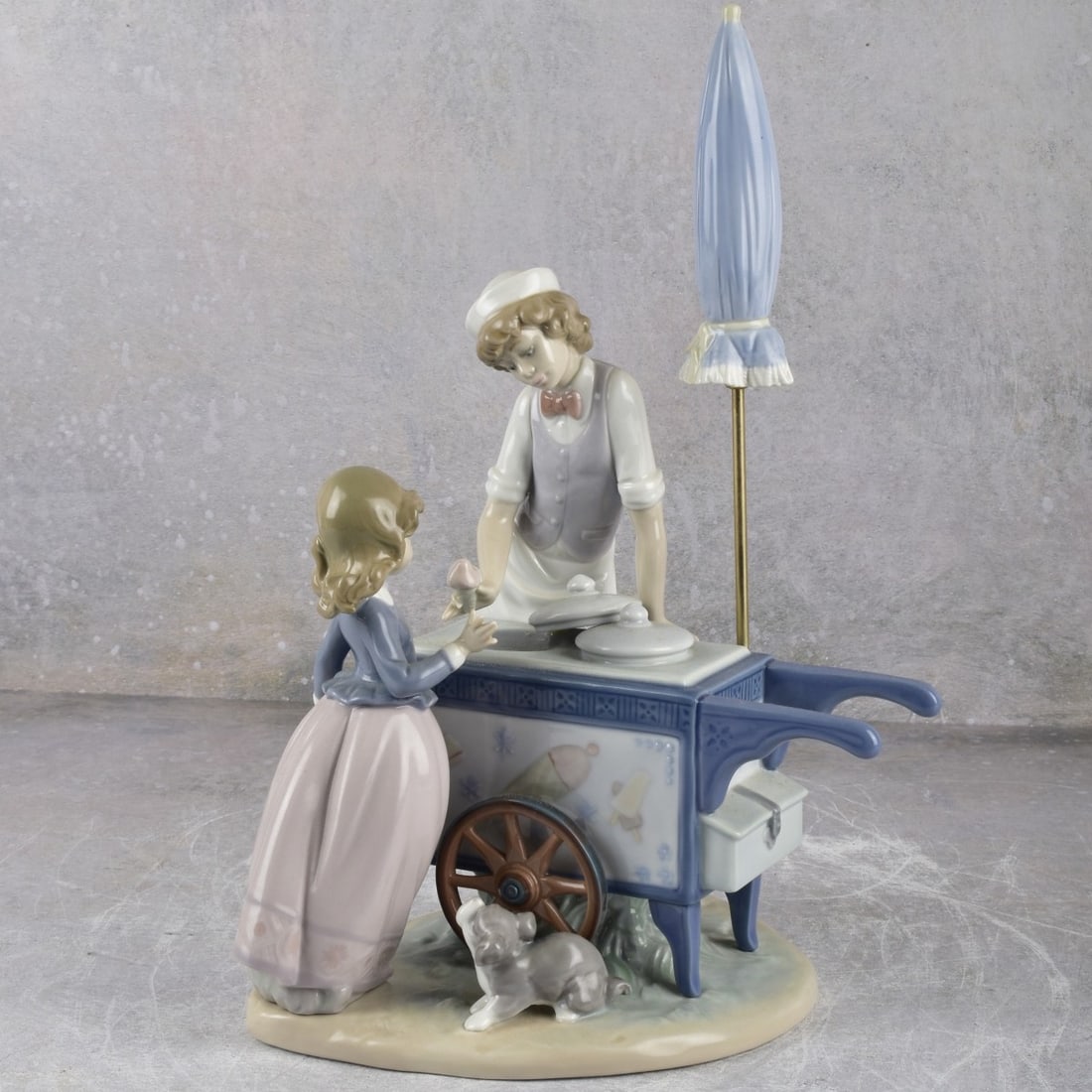 Lladro Spain "Ice Cream Vendor": Lladro Spain "Ice Cream Vendor" Gloss Porcelain Figurine. Designed by Antonio Ramos, issued dates: 1985-1995. Signed with LLADRO backstamp. Measures: 12-1/2" high, 7-1/2" wide, 7-3/4" deep. Kodner Gal