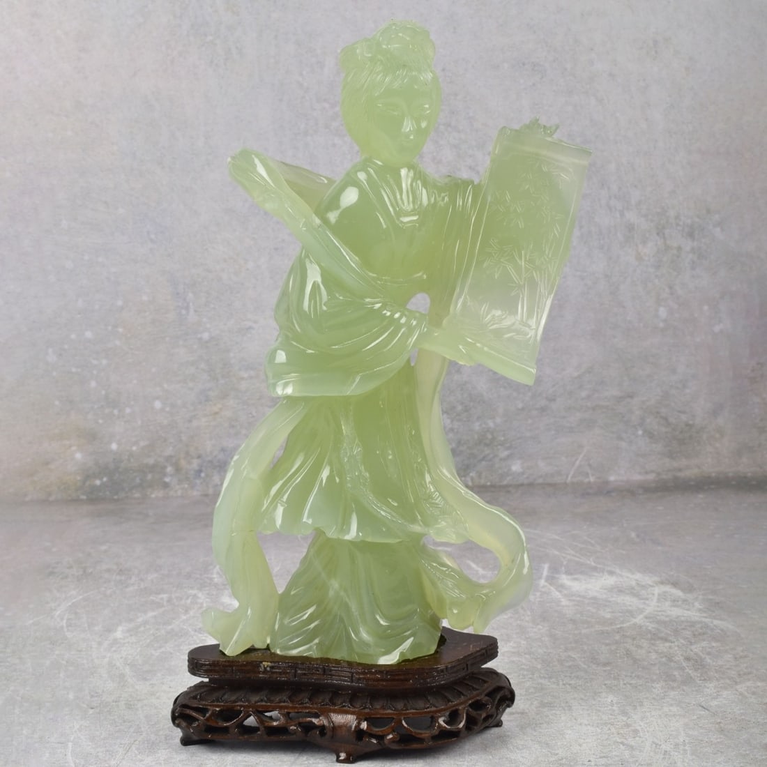 Carved Serpentine Sculpture of a Guanyin: Vintage Carved Serpentine Sculpture of a Guanyin Holding a Scroll Presented on a Carved Wood Base. Figure measures: 9-3/8" high, 5" wide, 2-1/4" deep. Kodner Galleries offers phone and absentee biddin