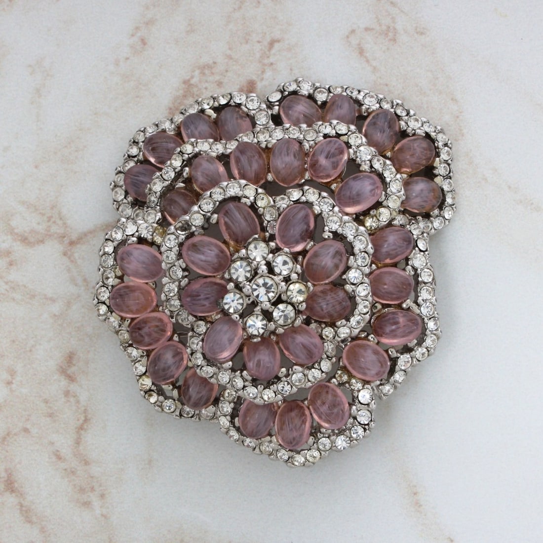 MCJ Fashion Brooch: Vintage MCJ Fashion Brooch. Set with pink stones, faux diamonds in white metal. Stamped MCJ. Measures 2" H, 1-7/8" W. Kodner Galleries offers phone and absentee bidding at a low, flat 21% buyer’s pr