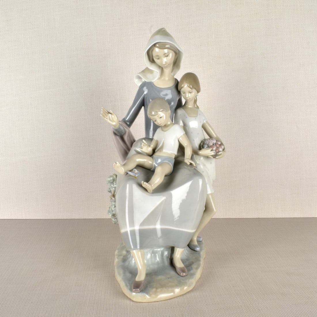Lladro Figurine of a Mother and Children: Lladro Figurine of a Mother and Children with a Young Girl Holding a Basket of Fruit and all Looking at a Butterfly. Properly marked on the bottom. Measures: 15-3/4" H, 8-1/2" W, 9-3/4" D. Kodner Gall