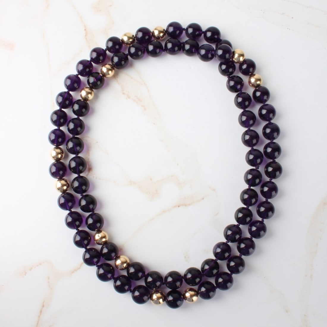 Amethyst and 14K Necklace: Large Vintage Single Strand 12.0mm Gem Quality Amethyst Bead and 10mm 14 Karat Yellow Gold Bead Necklace. 38" L. Approx. weight: 157.62 grams. Kodner Galleries offers phone and absentee bidding at a l