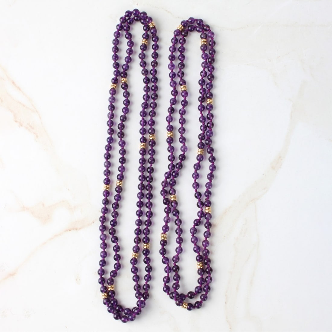 Amethyst and 14K Necklaces: Two Vintage Single Strand 5mm Amethyst Bead Necklaces with 14 Karat Yellow Gold Spacers. Measure 32" L and 34" L. Approx. total weight: 49.11 grams. Kodner Galleries offers phone and absentee bidding
