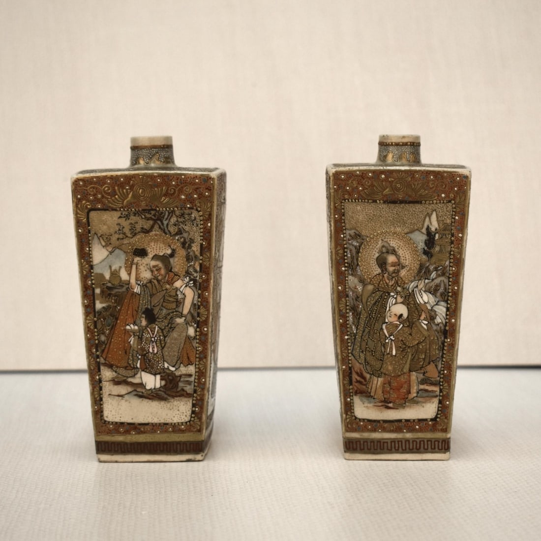 Japanese Satsuma Square Vases: Pair of Japanese Satsuma Square Tapered Vases. Each panel decorated in different scenes of men and women in elaborate dress with heavy gilt.. Unsigned. Late 20th century. Measures: 5-1/2" H, 2-1/2" W,
