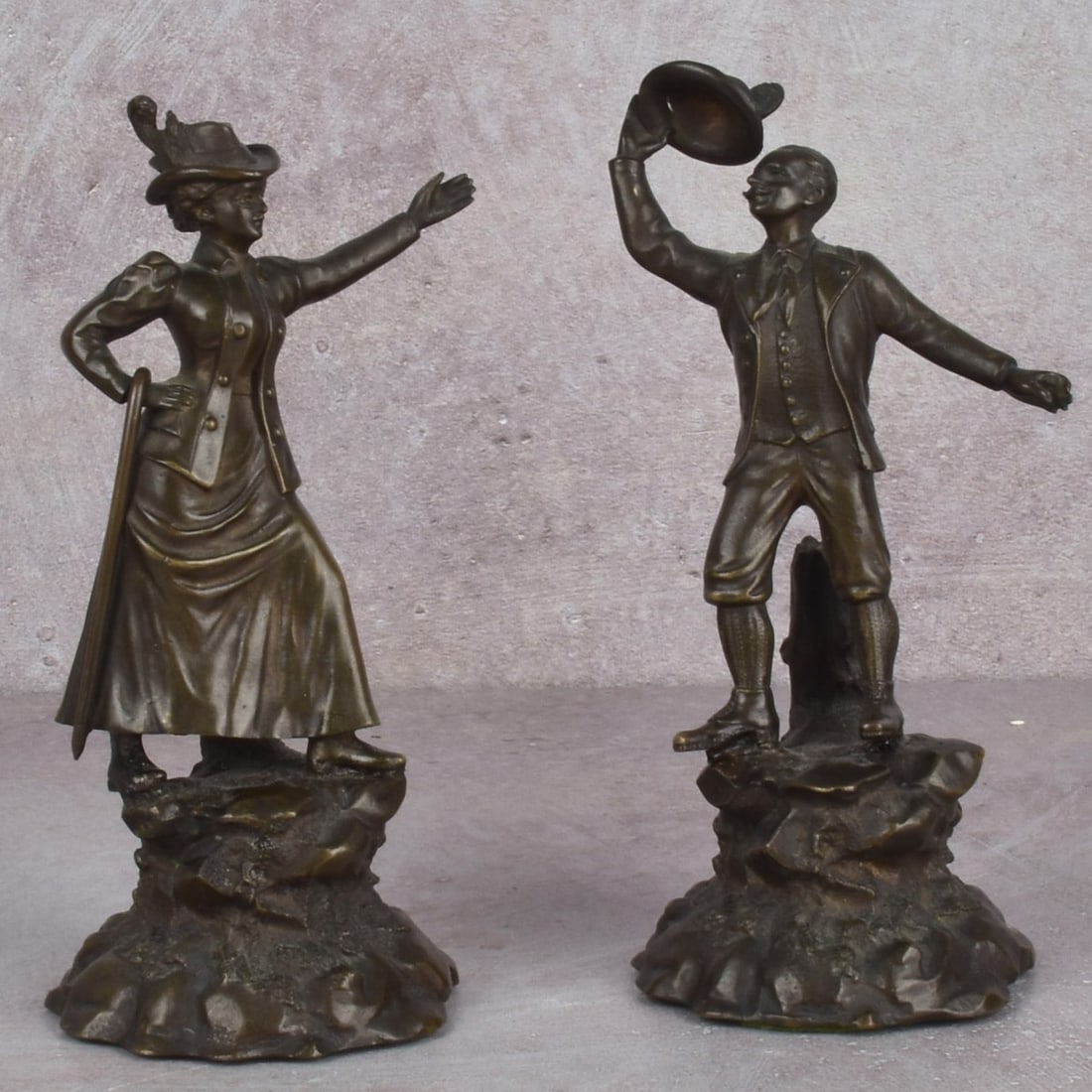 Antique Victorian Bronze Couple: Antique Victorian Bronze Couple. One sculpture of a gentleman tipping his hat and the other of lady with a walking stick each with an open tree trunk to accommodate a flower stem. Overall measures: he