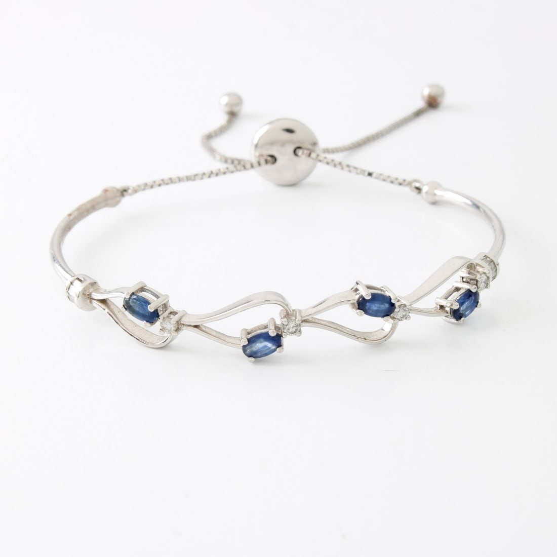 Sapphire, Diamond and 14K Bracelet: Contemporary Design Oval Cut Sapphire, Round Brilliant and Baguette Cut Diamond and 14 Karat White Gold Cuff Bangle Bracelet. Sapphires with good color. Adjustable length. Approx. weight: 8.76 grams.