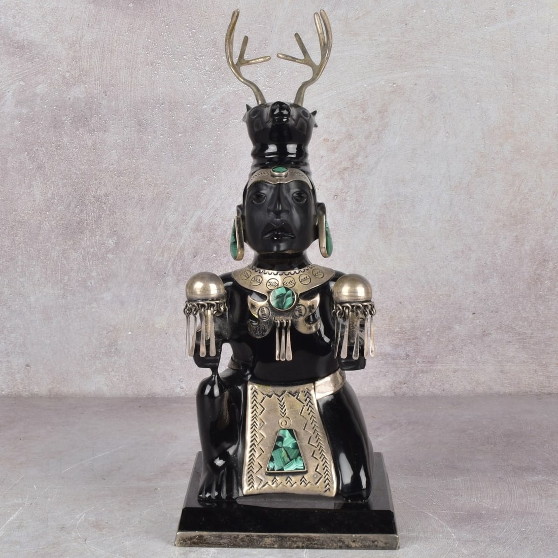 Obsidian and Sterling Silver Sculpture: Aztec Style Obsidian and Sterling Silver Sculpture with Malachite Insets. Mexico 20th century. Depicting a crouching figure wearing an animal headdress with antlers, holding ceremonial rattles,