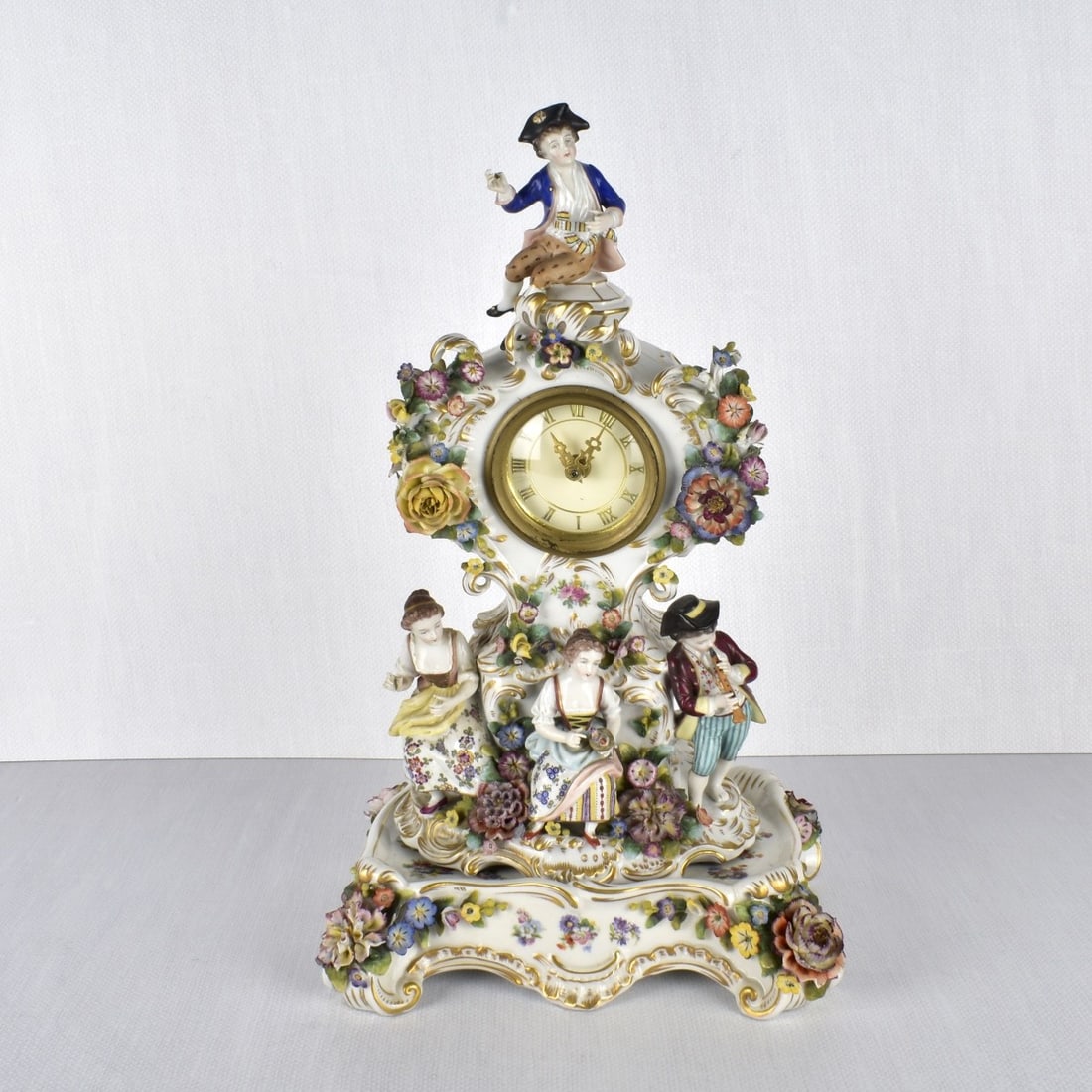 Royal Vienna Porcelain Clock: Royal Vienna Porcelain Figural Clock on a Matching Porcelain Stand. One gentleman playing music to two seated women with another gentleman on the very top final of the clock. Both clock and stand