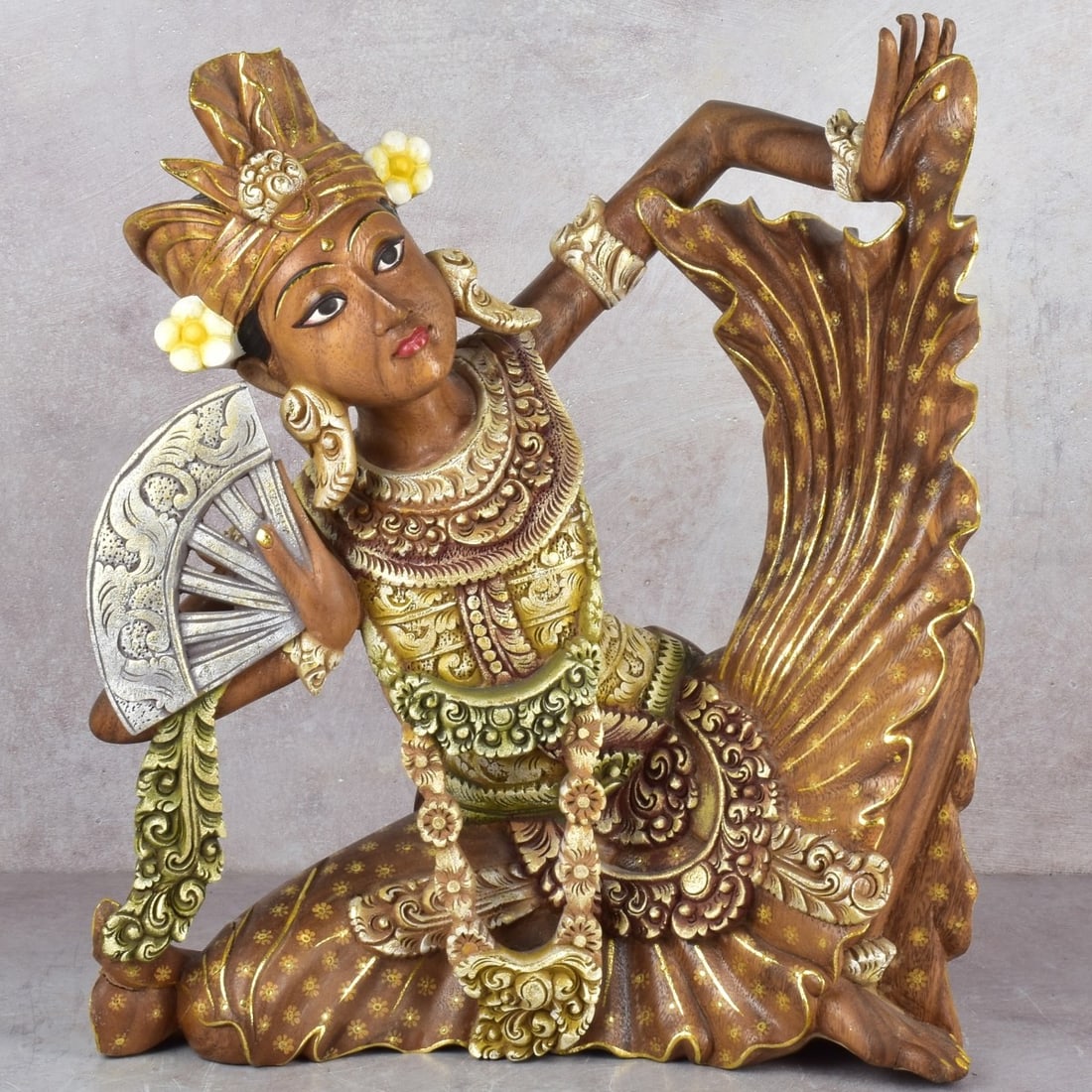 Carved Balinese Dancer: Carved and Painted Traditional Balinese Female Fan Dancer. Measures: 16-1/4" high, 14" wide, 6" deep. Kodner Galleries offers phone and absentee bidding at a low, flat 21% buyer’s premium without