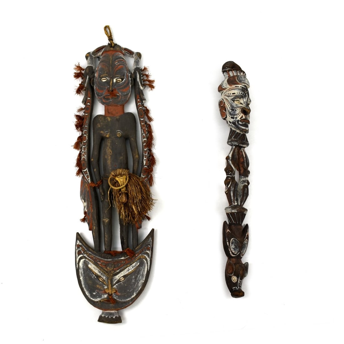 African Wall Hanging Sculptures: Grouping of Two African Polychrome Wood Carved Wall Hanging Sculptures with Sea Shell Eyes. Tallest measures 39" x 11" . Other sculpture measures 32" x 4-1/2". Kodner Galleries offers phone and